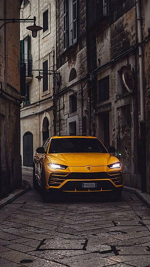 Yellow Lamborghini Urus SUV Parked in a Narrow European Cobblestone Alley HD phone wallpaper