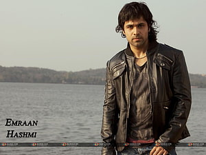 Emraan Hashmi in a black leather jacket standing by a calm lake with distant hills HD wallpaper