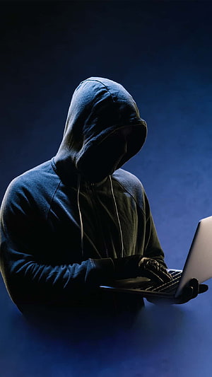 Anonymous Hacker in Hoodie Typing on Laptop in Dark Blue Atmosphere HD phone wallpaper