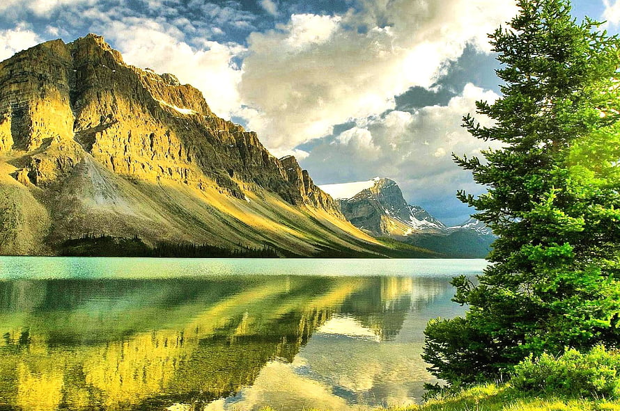 Serene Mountain Lake Reflection with Golden Slopes and Evergreen Trees Under Dramatic Skies HD wallpaper