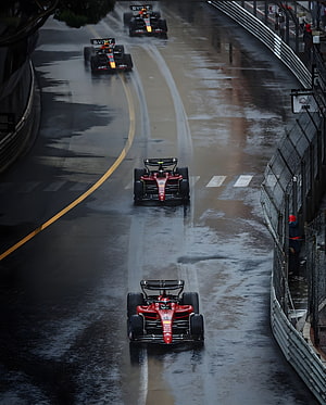 Ferrari and Red Bull Formula 1 cars racing on a wet street circuit in Monaco HD phone wallpaper
