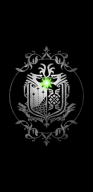 Monster Hunter World Emblem with Glowing Green Gem and Ornate Silver Crest on Black Background HD phone wallpaper