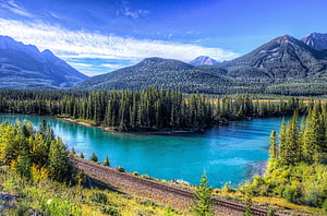 Turquoise Mountain Lake Surrounded by Dense Evergreen Forest and Railway Tracks HD wallpaper