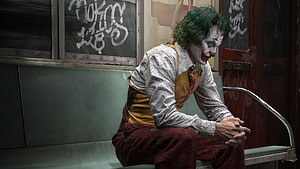 Joker sitting on a subway bench in a grimy urban setting HD wallpaper