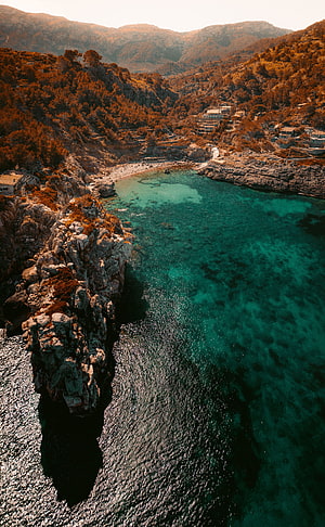 Aerial View of Turquoise Bay with Rocky Cliffs and Coastal Village HD phone wallpaper