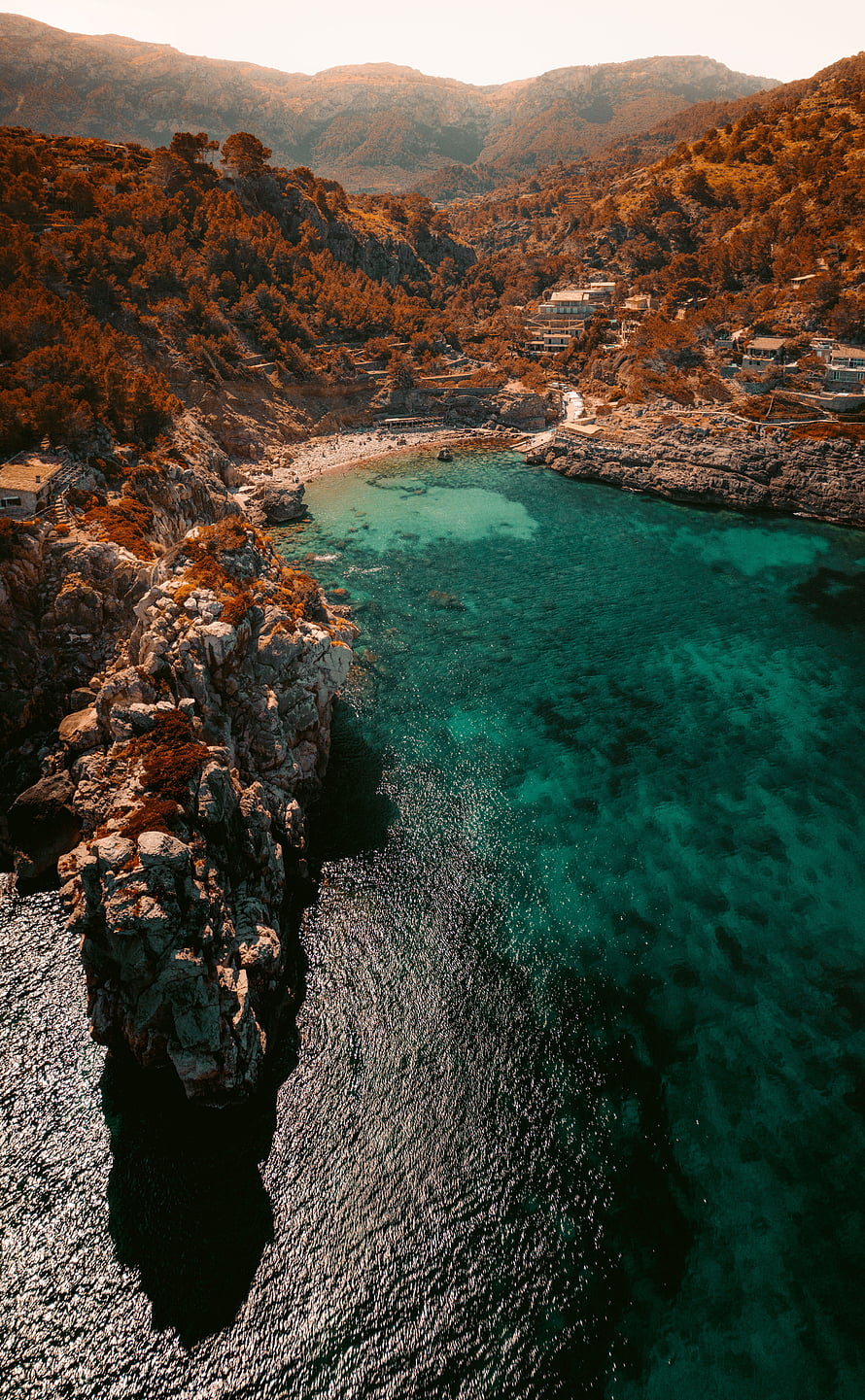 Aerial View of Turquoise Bay with Rocky Cliffs and Coastal Village HD phone wallpaper