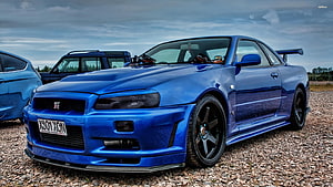 Blue Nissan Skyline GT-R R34 Widebody Coupe with Rear Wing on Gravel HD wallpaper