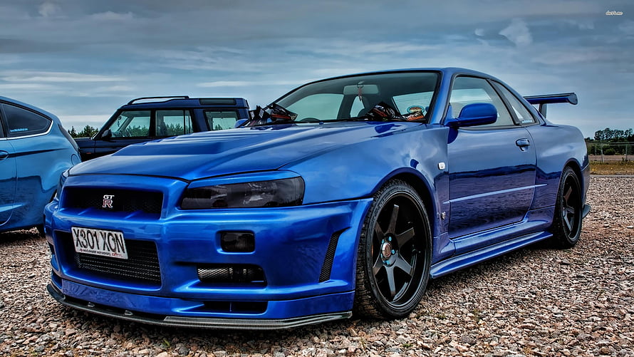 Blue Nissan Skyline GT-R R34 Widebody Coupe with Rear Wing on Gravel HD wallpaper