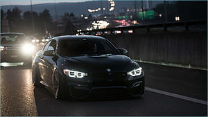 Black BMW M4 Coupe Driving on Highway at Dusk with LED Headlights HD wallpaper