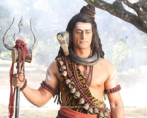 Mahadev as Lord Shiva with trident, cobra, and rudraksha beads in a forest setting HD wallpaper
