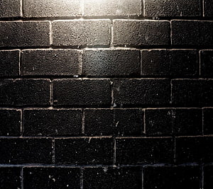 Dark Textured Brick Wall Surface with Dramatic Lighting and Deep Shadows HD wallpaper