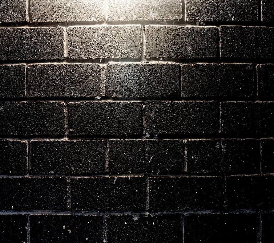 Dark Textured Brick Wall Surface with Dramatic Lighting and Deep Shadows HD wallpaper