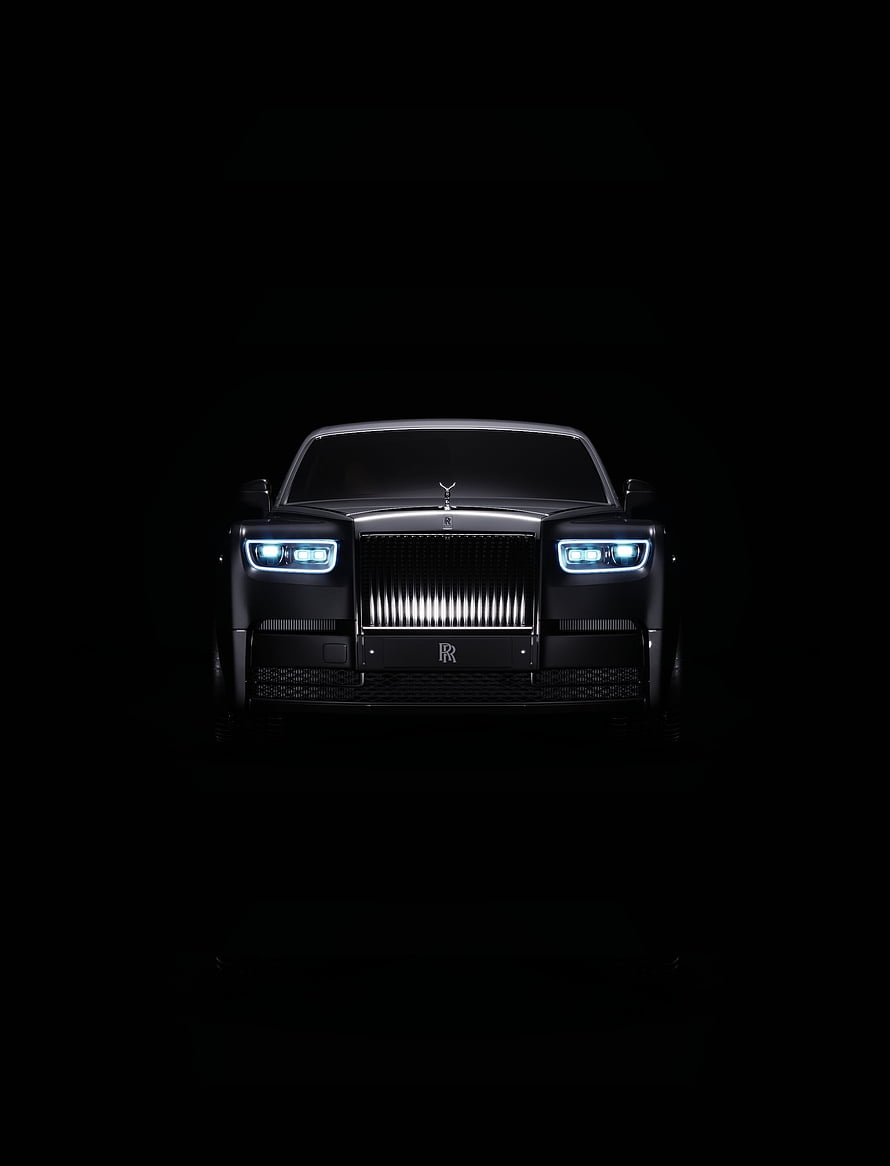 Rolls-Royce Phantom Front View with Illuminated Headlights Against Black Background HD phone wallpaper