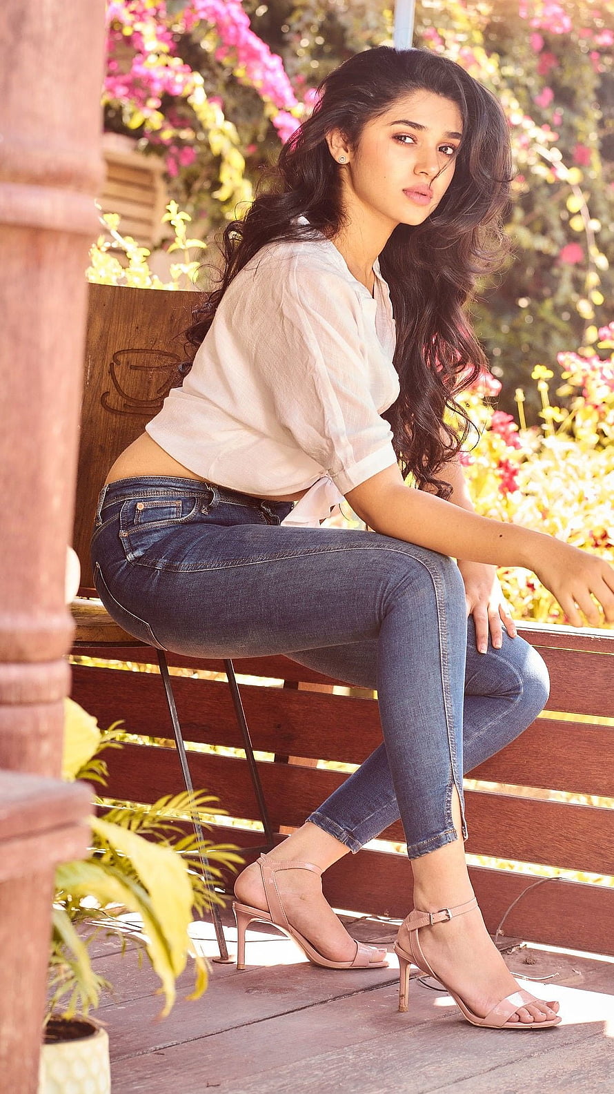 Kriti Shetty in White Blouse and Blue Jeans Sitting on Wooden Bench HD phone wallpaper
