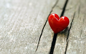 Glossy Red Heart Ornament Resting on Weathered Wooden Planks HD wallpaper