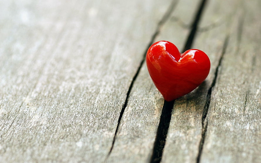 Glossy Red Heart Ornament Resting on Weathered Wooden Planks HD wallpaper