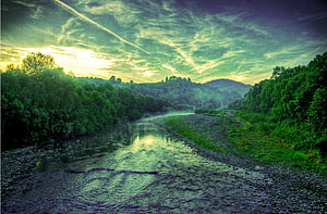 Serene River Valley at Dusk with Lush Forests and Dramatic Clouds HD wallpaper
