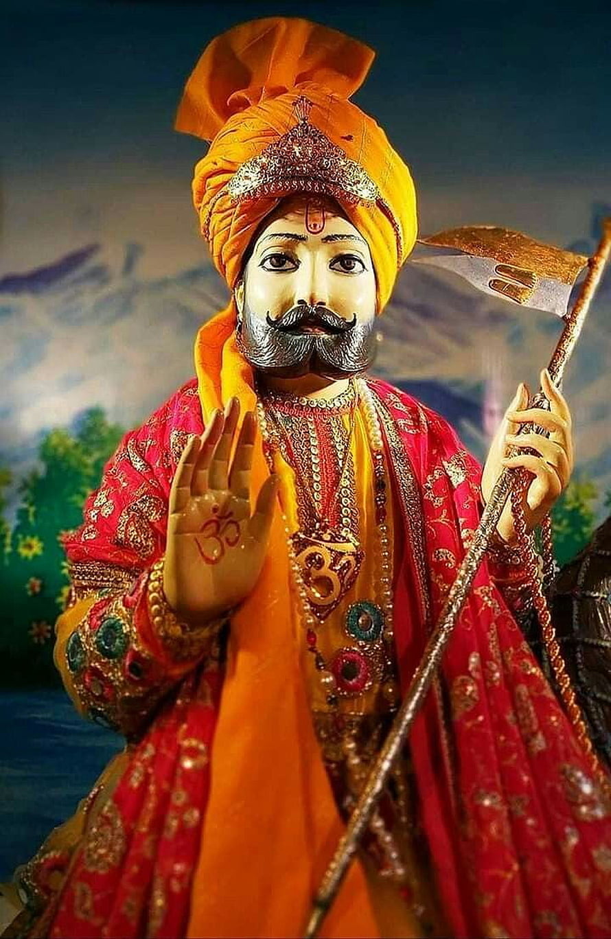 Ramdevji Statue in Vibrant Orange Turban and Red Robes Holding a Staff HD phone wallpaper