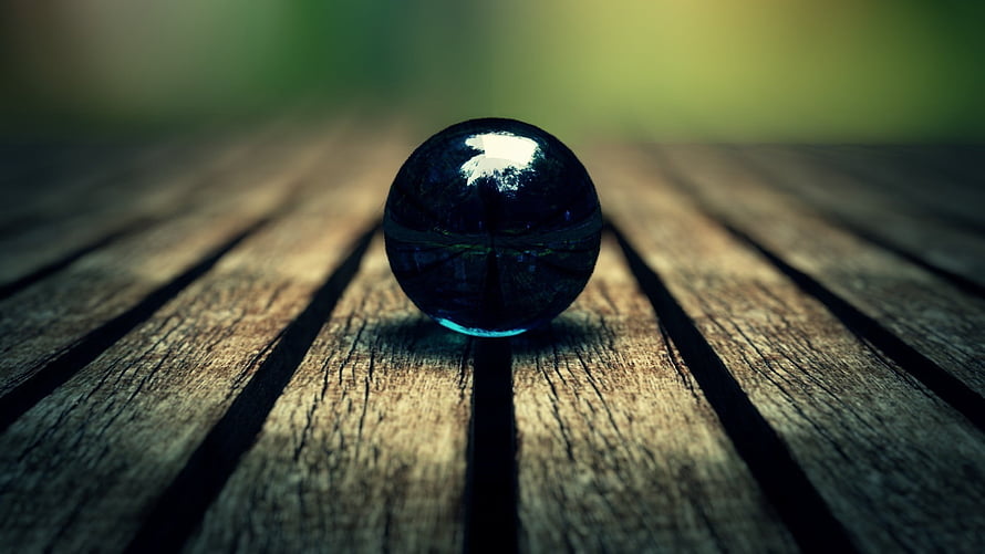 Dark Glass Sphere Resting on Weathered Wooden Planks with Soft Green Background HD wallpaper