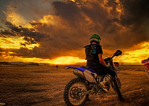 Motorcyclist on a dirt bike silhouetted against a dramatic golden sunset sky HD wallpaper