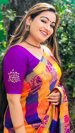 Smiling Woman in Vibrant Orange and Purple Floral Saree with Traditional Jewelry HD phone wallpaper