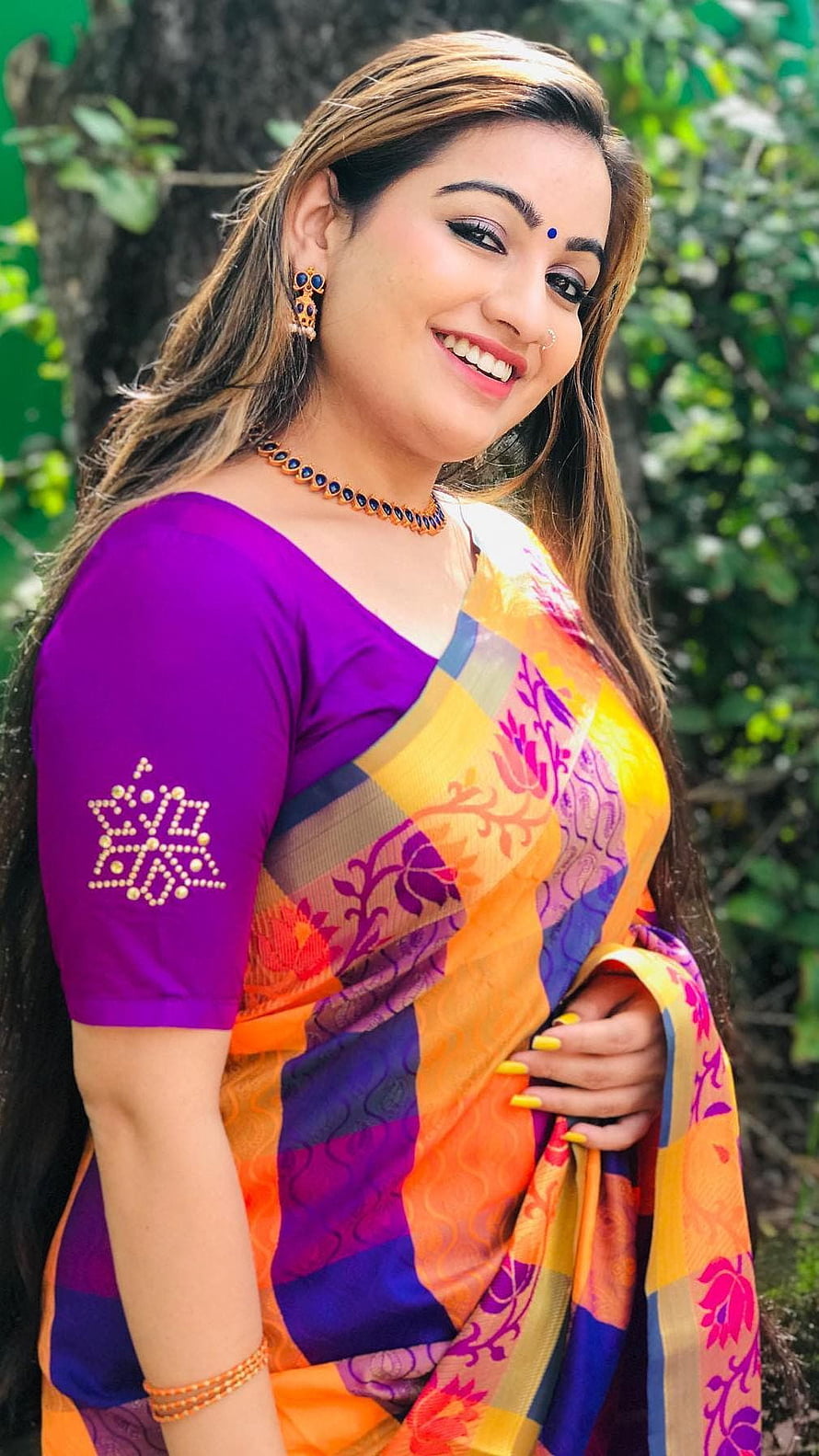 Smiling Woman in Vibrant Orange and Purple Floral Saree with Traditional Jewelry HD phone wallpaper