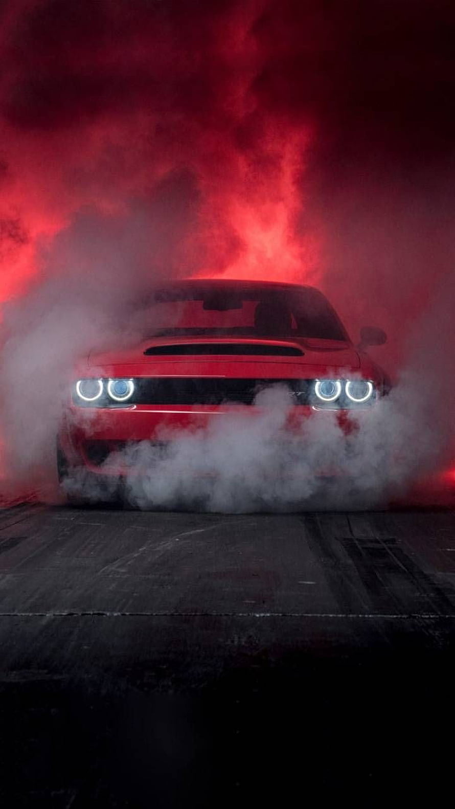 Red Dodge Challenger SRT Hellcat emerging from thick smoke with glowing headlights under dramatic red lighting HD phone wallpaper