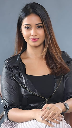 Nivetha Thomas in a Black Leather Jacket and White Pleated Skirt HD phone wallpaper