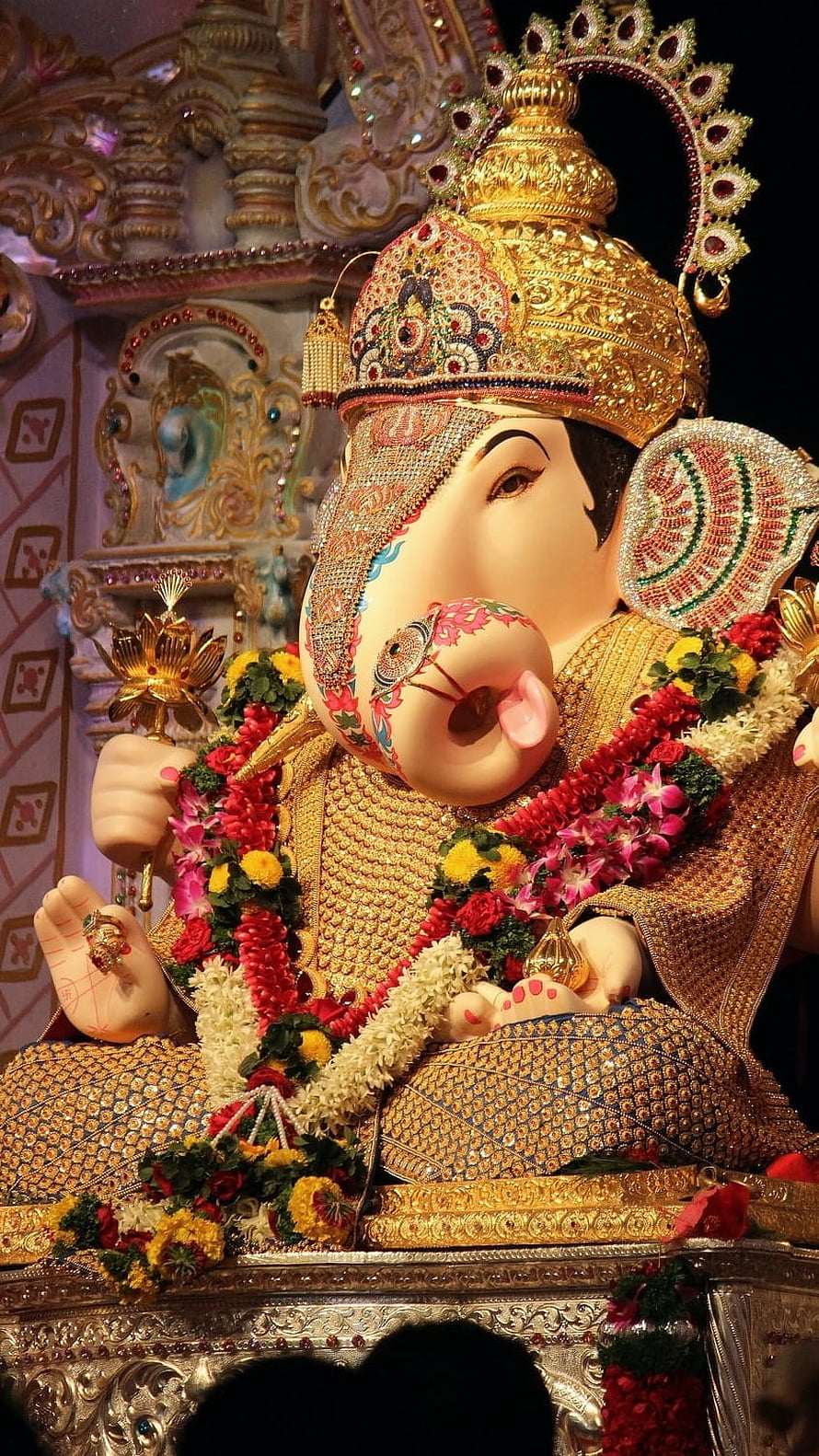 Ornate Ganesha Temple Idol Adorned With Gold Crown And Vibrant Flower Garlands HD phone wallpaper