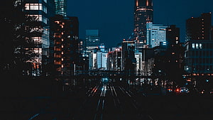 Moody Urban Skyline at Night with Illuminated High-Rise Buildings and Street Lights HD wallpaper