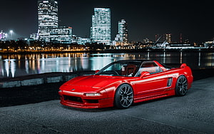 Red Honda NSX sports car parked on waterfront at night with illuminated city skyline HD wallpaper
