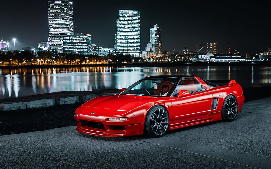 Red Honda NSX sports car parked on waterfront at night with illuminated city skyline HD wallpaper