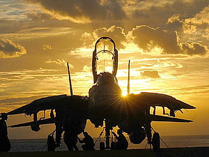 F-14 Tomcat fighter jet silhouette on carrier deck at golden sunset HD wallpaper