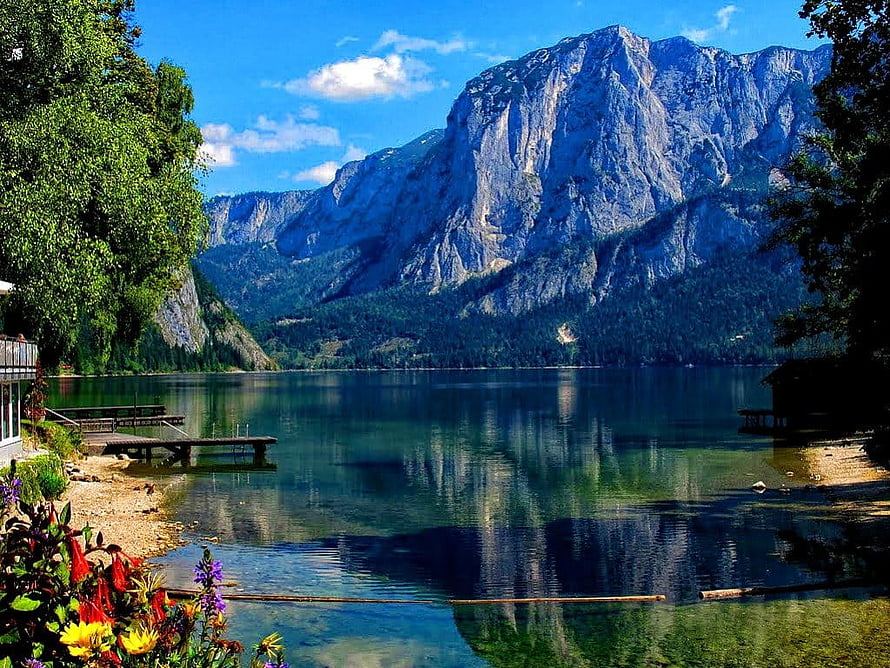 Serene Alpine Lake with Mountain Reflections, Wooden Pier, and Vibrant Shoreline Flowers HD wallpaper