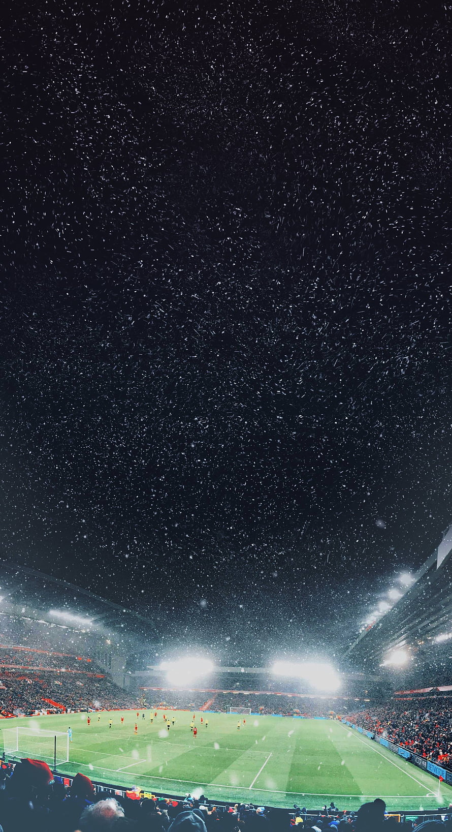 Snowfall Over a Lit Soccer Stadium at Night with Players on the Pitch HD phone wallpaper