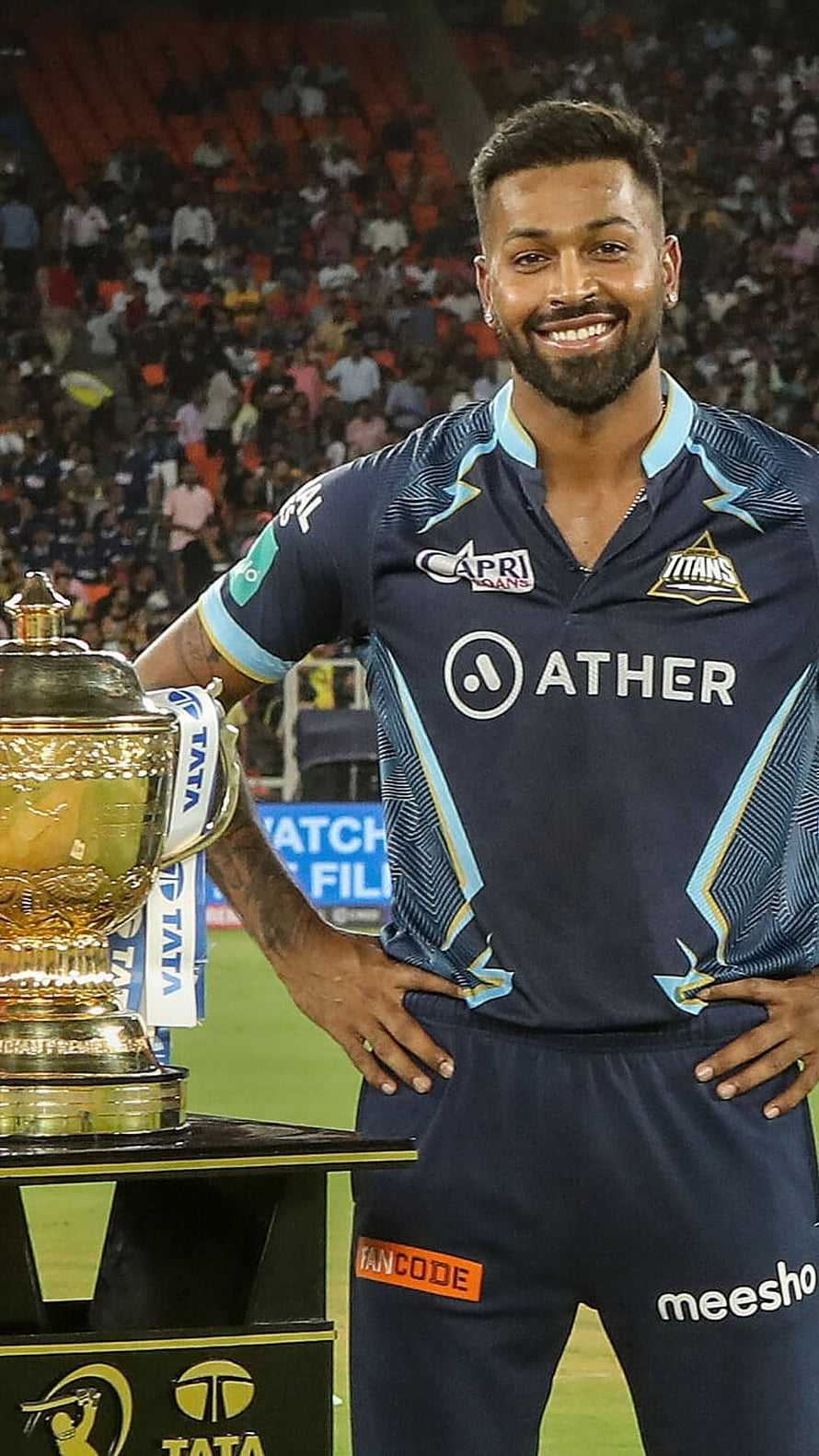Hardik Pandya in Gujarat Titans kit standing beside the IPL trophy at a stadium HD phone wallpaper