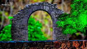 Weathered Stone Arch Ruin Framing Vibrant Green Foliage in a Lush Garden Setting HD wallpaper