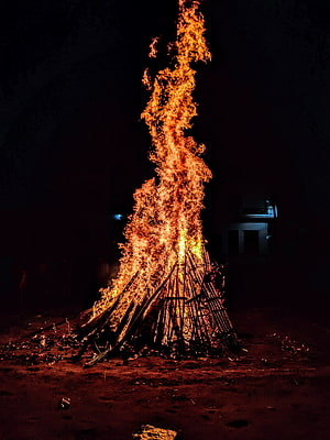 Towering Holika Dahan bonfire burning brightly against the dark night sky HD phone wallpaper