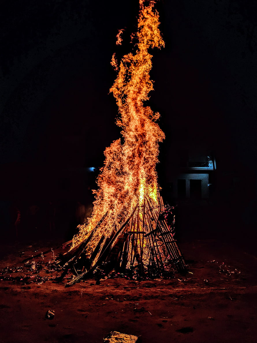 Towering Holika Dahan bonfire burning brightly against the dark night sky HD phone wallpaper
