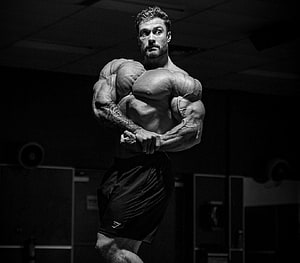 Chris Bumstead Classic Bodybuilding Pose in Black and White Gym Setting HD wallpaper