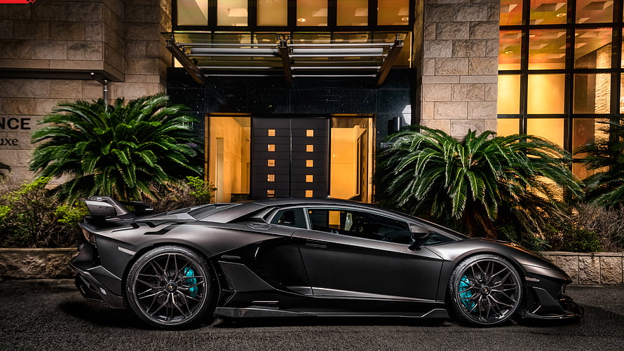 Matte Black Lamborghini Aventador SVJ Parked at Night in Front of a Luxury Hotel Entrance HD wallpaper