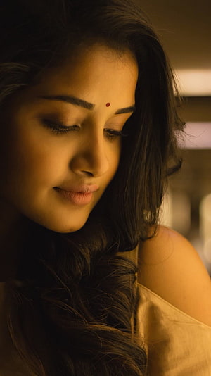 Anupama Parameshwara in a warm, contemplative close-up portrait with soft golden lighting HD phone wallpaper