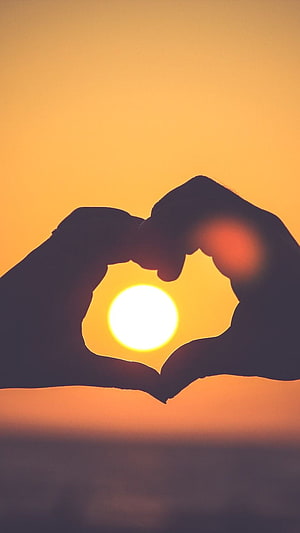 Silhouette of Hands Forming a Heart Shape Around a Golden Sunset Over the Ocean HD phone wallpaper