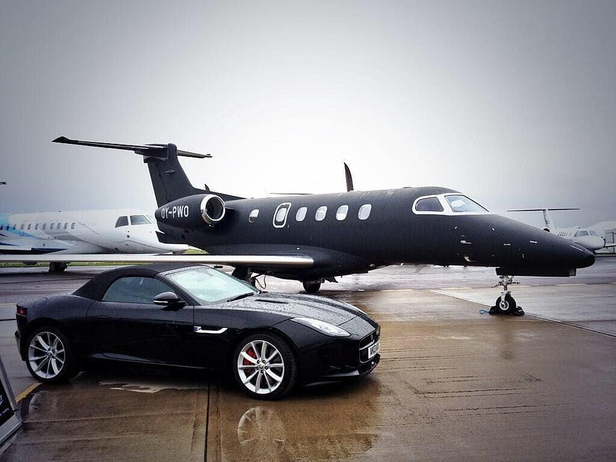 Black Jaguar F-Type Convertible Parked in Front of a Private Jet on a Rainy Tarmac HD wallpaper