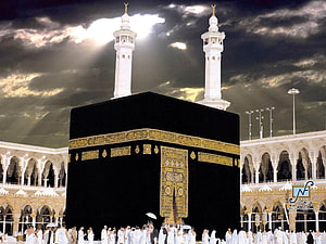 The Kaaba at Masjid Al Haram in Mecca with pilgrims and minarets under a dramatic sky HD wallpaper