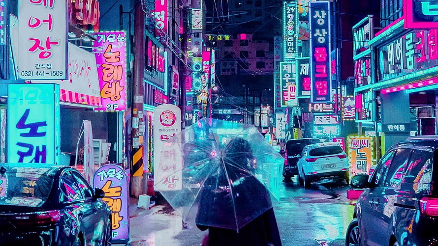 Neon-lit Korean street at night with a person holding a transparent umbrella in the rain HD wallpaper