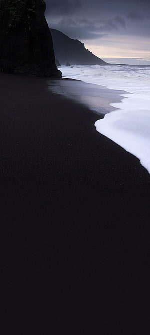 Moody Black Sand Beach with Dark Cliffs and Foaming Ocean Waves at Dusk HD phone wallpaper