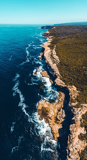 Aerial View of Dramatic Coastal Cliffs and Turquoise Ocean Waves HD phone wallpaper