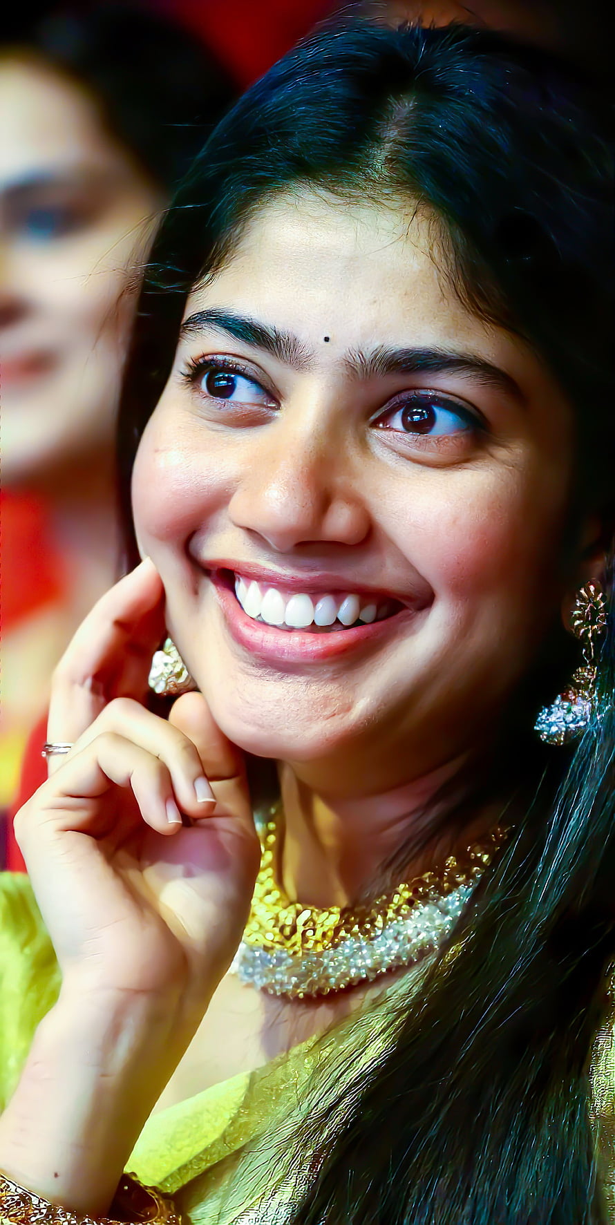 Sai Pallavi in a vibrant yellow saree with ornate gold jewelry and a warm smile HD phone wallpaper