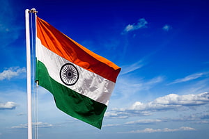 Indian National Flag Waving Against a Bright Blue Sky with Scattered Clouds HD wallpaper